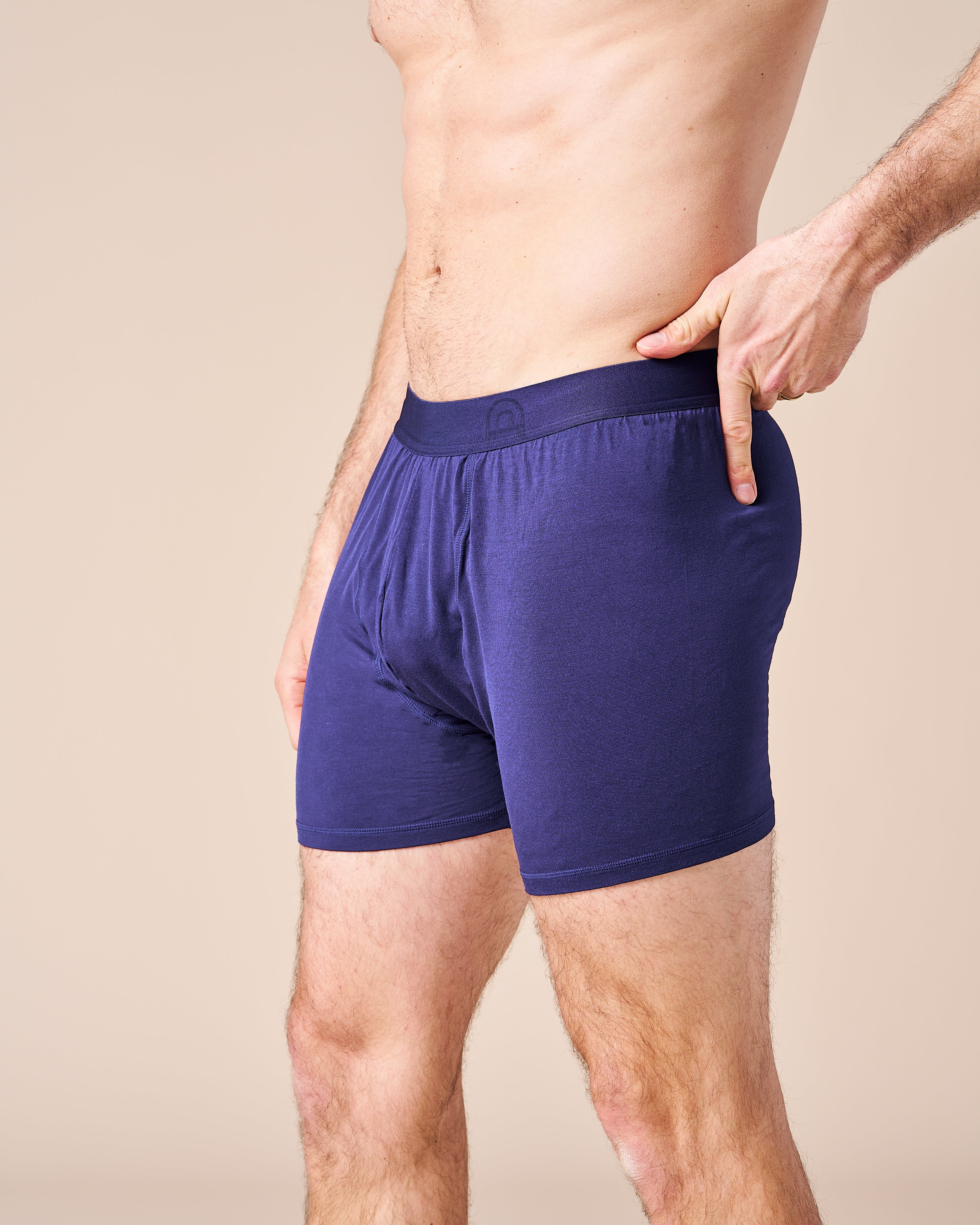 A male model comfortably wearing the Fruitful Navy Boxer, underwear designed for male fertility